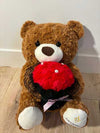6. A Brown Bear Sits Holding Flowers